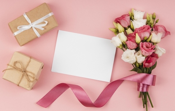 Букет эустомы с лентой на розовом фоне с подарками и белым листом