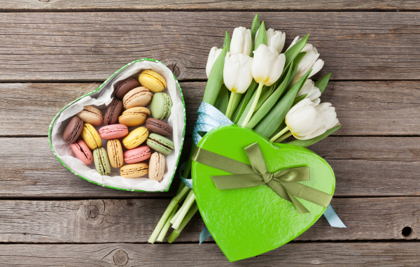 Букет белых тюльпанов на столе с коробкой печенья макарун