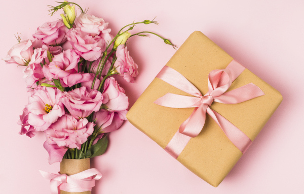 Большой букет эустомы с подарком на розовом фоне