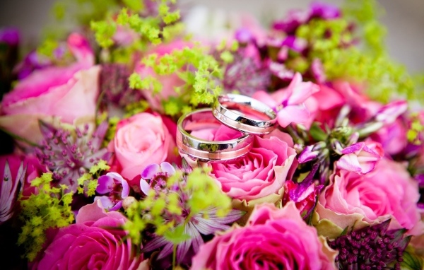 Два обручальных кольцо на букете розовых цветов