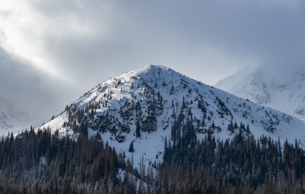 Высокая заснеженная гора под пасмурным небом