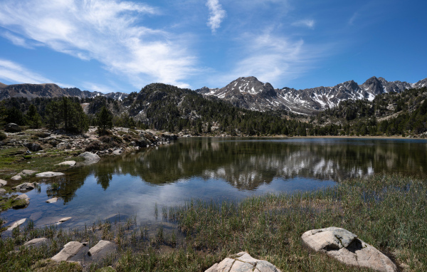 Горы отражаются в воде озера с большими камнями