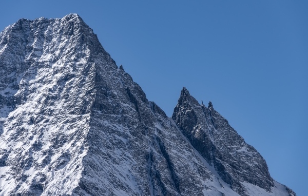 Крутая вершина горы в снегу на фоне голубого неба