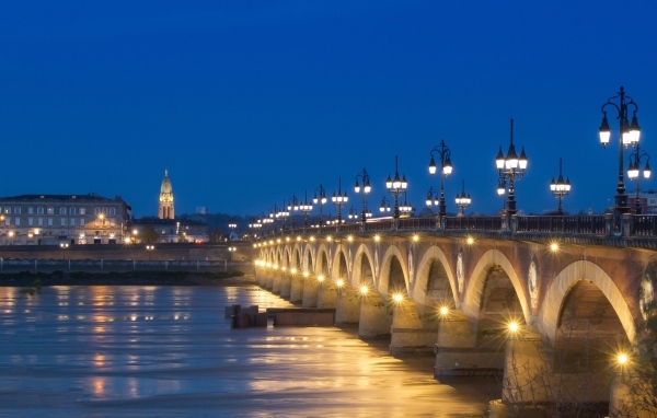 Красивый светящийся мост через реку ночью 