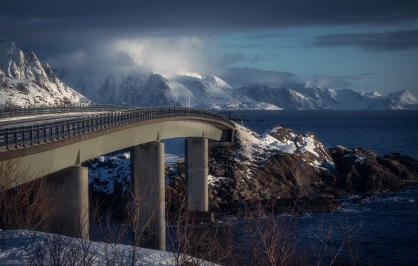 Мост через реку в заснеженных горах 