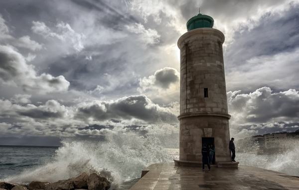 Волны бьются о маяк под красивым небом