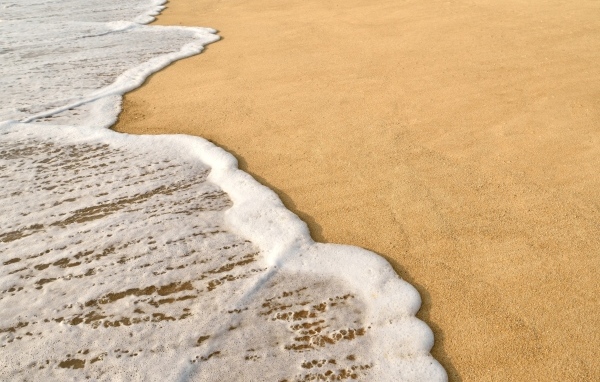 Белая пена на горячем песке на пляже