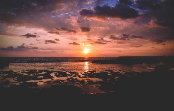 Закат яркого летнего солнца в небе над морем