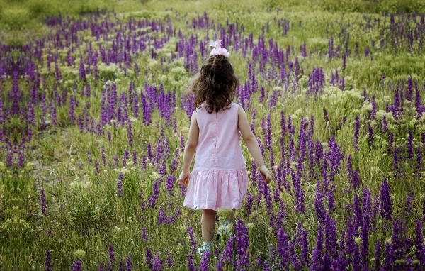 Девочка в розовом платье гуляет по полю с цветами