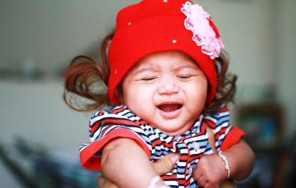 Девочка в красной шапке плачет на руках