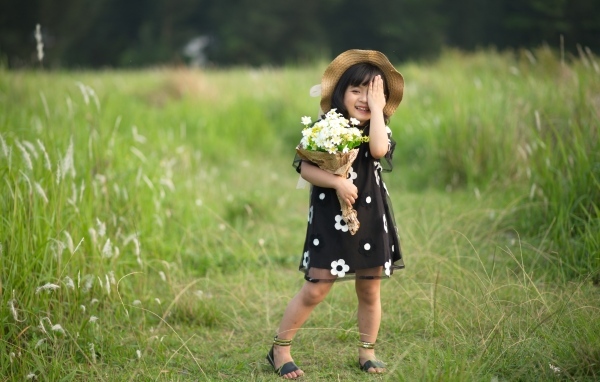 Девочка азиатка в шляпе с букетом цветов