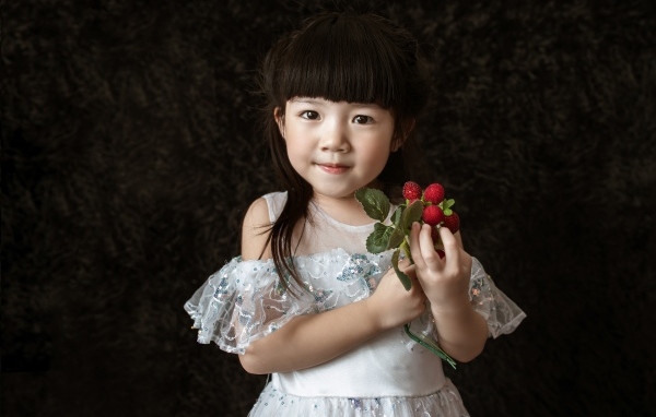 Девочка азиатка в белом платье с ягодами в руке