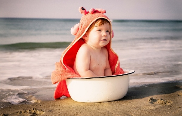 Ребенок в миске на берегу моря