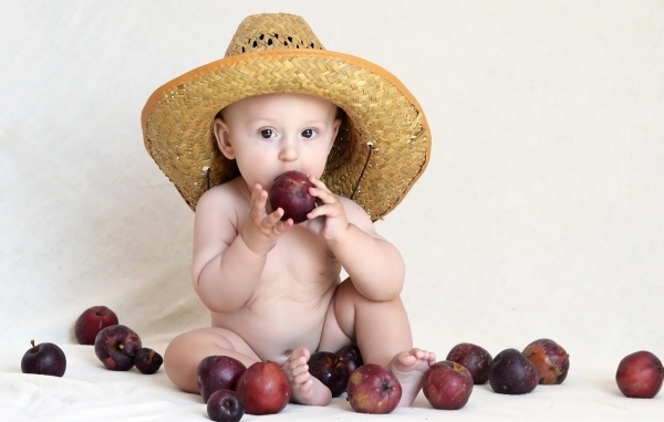 Малыш в шляпе грызет яблоки