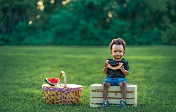 Темнокожий мальчик ест арбуз на природе