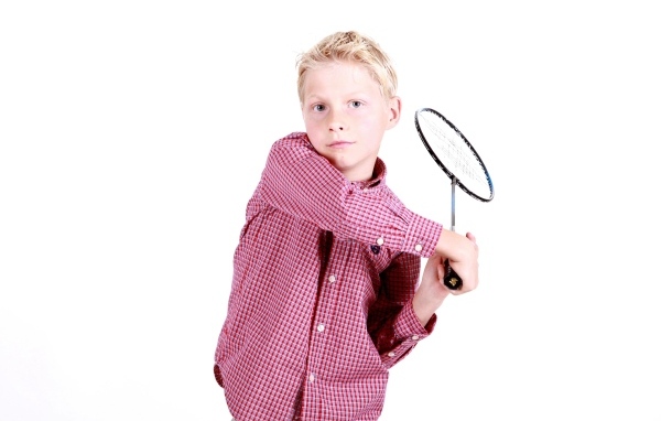 Мальчик в рубашке с ракеткой в руках на белом фоне
