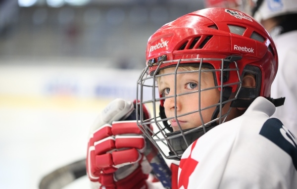 Мальчик в красном шлеме хоккеиста на поле