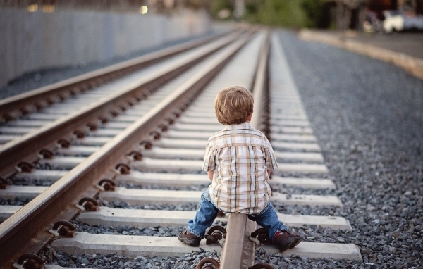 Мальчик сидит на железнодорожных рельсах