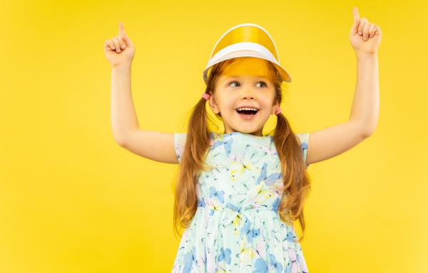 Веселая девочка в платье на желтом фоне