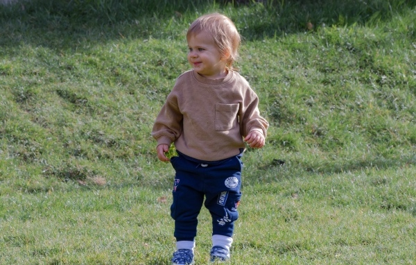 Веселый маленький мальчик гуляет на природе