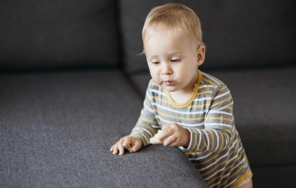 Любопытный маленький ребенок у дивана