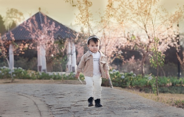 Милый мальчик гуляет по дороге у дома