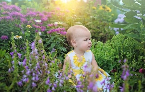 Милая девочка в платье сидит в цветах
