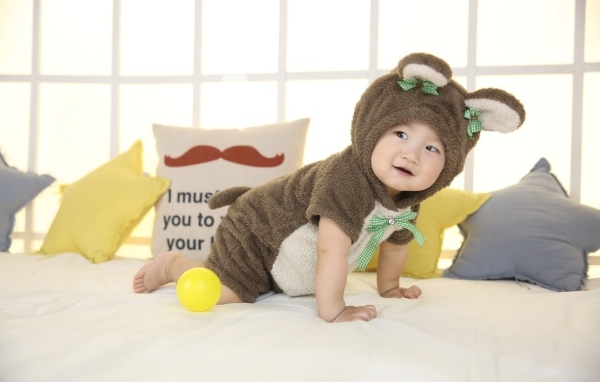 Смешной ребенок азиат в костюме на кровати