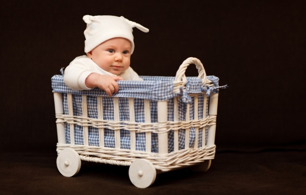 Маленький ребенок в колыбели на коричневом фоне