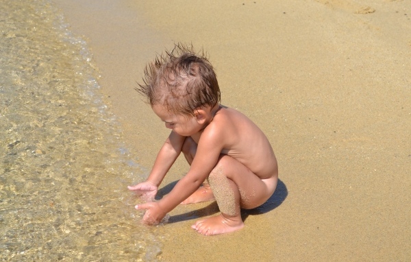 Маленький мальчик на пляже у моря на песке