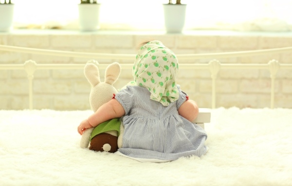 Маленькая девочка обнимает игрушечного зайца