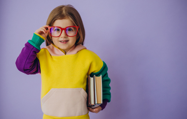 Маленькая девочка в очках с книгами в руке