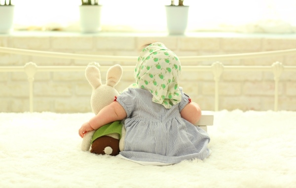 Маленькая девочка сидит с игрушкой