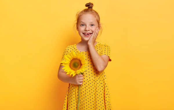Маленькая рыжеволосая девочка с подсолнухом в руках