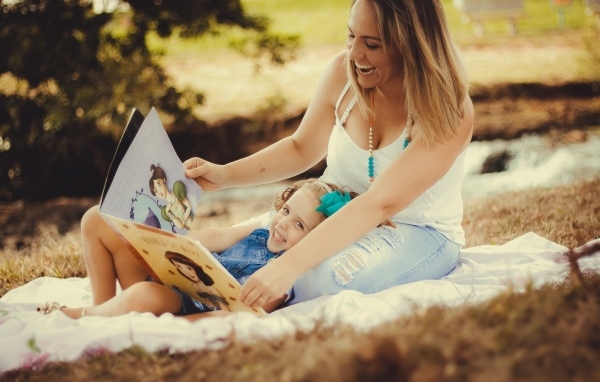 Мама читает дочери книгу на природе