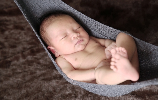 Новорожденный спящий малыш в вязаном гамаке