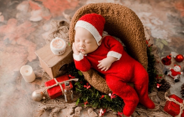 Спящий новорожденный ребенок в красном новогоднем костюме