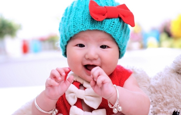 Улыбающаяся девочка в зеленой вязаной шапке