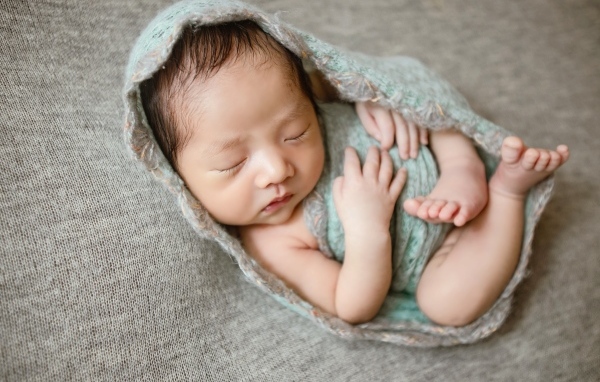 Крошечный новорожденный малыш на сером фоне