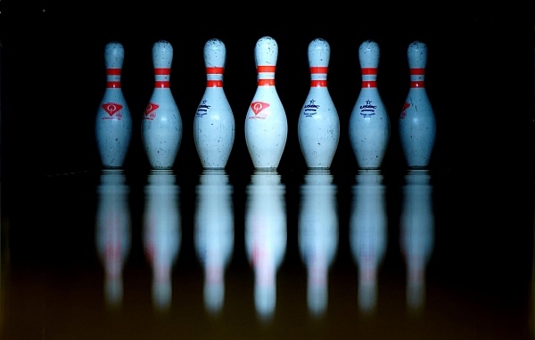 Кегли для боулинга отражаются в черной поверхности 