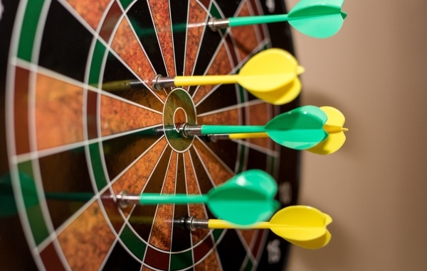 Желтые и зеленые дротики в мишени 
