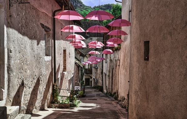 Розовые зонтики украшают узкую улицу