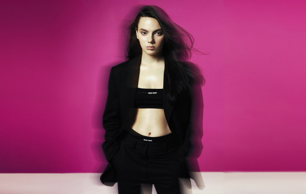 Актриса Дафни Кин стоит у розовой стены