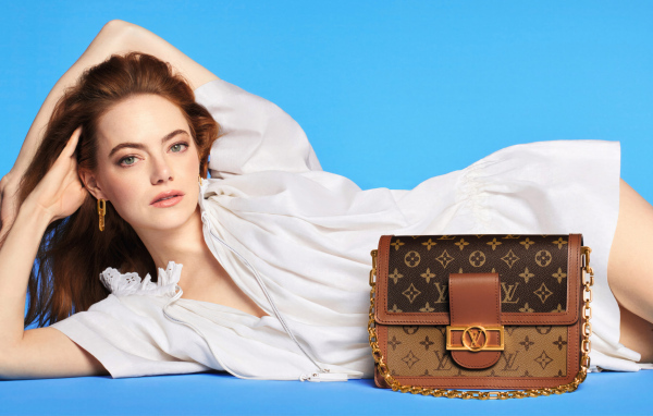 Актриса Эмма Стоун с сумочкой Louis Vuitton на голубом фоне