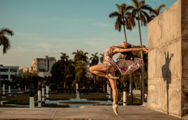 Девушка балерина в платье в красивой позе в лучах солнца