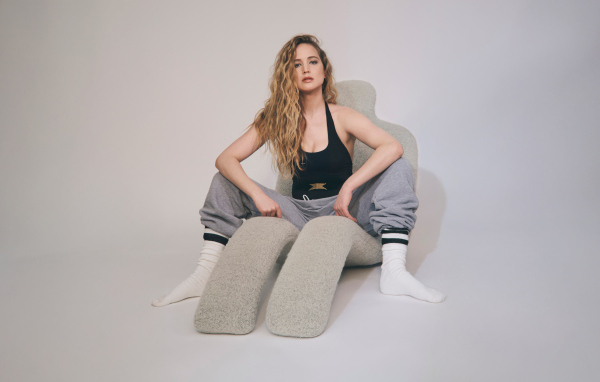 Красивая актриса Дженнифер Лоуренс  сидит на сером кресле