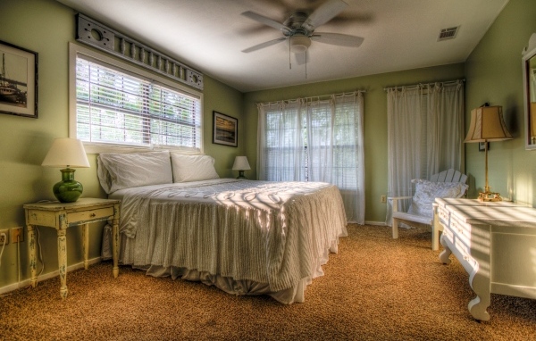 Спальня в зеленых тонах с высокой кроватью 