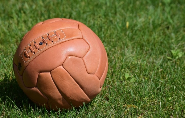Коричневый кожаный мяч на зеленой траве 