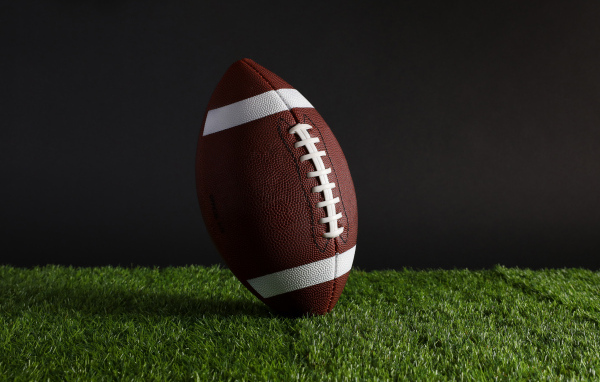 Новый кожаный мяч для американского футбола на траве
