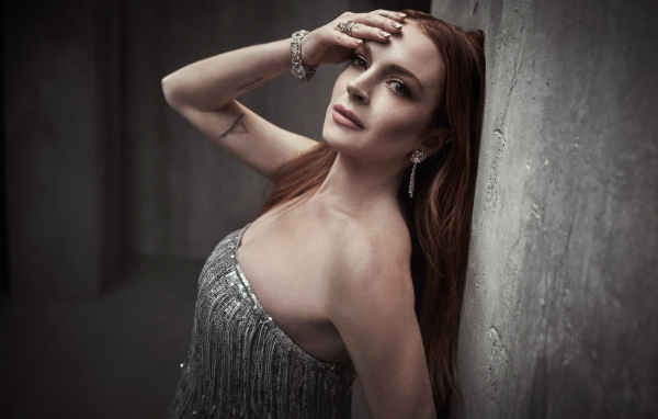 Рыжеволосая актриса Линдси Лохан стоит у стены